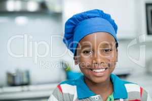 Smiling boy in chefs hat at home