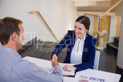 Businesswoman shaking hands with man at desk