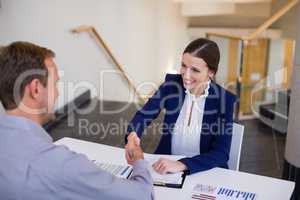 Businesswoman shaking hands with man at desk