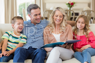 Parents and kids sitting together on sofa with photo album