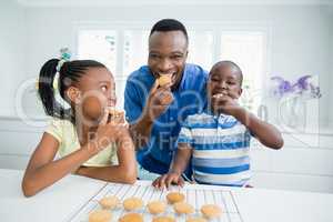 Father and kids eating cookies at home