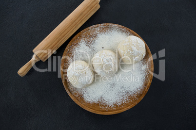 Rolling pin with pizza dough and flour on rolling board