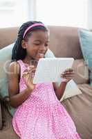 Girl sitting on sofa and using digital tablet in living room
