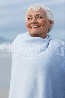 Senior woman wrapped in shawl at beach