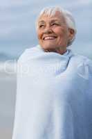 Senior woman wrapped in shawl at beach