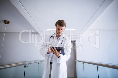 Doctor using digital tablet in corridor