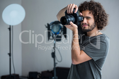 Happy male photographer with digital camera in studio