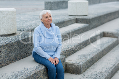 Thoughtful senior woman sitting on the steps