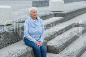 Thoughtful senior woman sitting on the steps