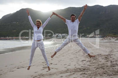 Mature couple jumping in air on the beach