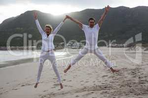 Mature couple jumping in air on the beach