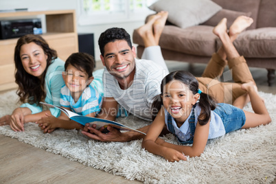 Portrait of parents and children lying on rug and reading book