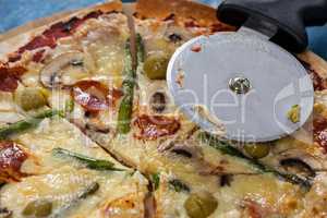 Delicious pizza served on pizza tray with cutter and knife on wooden plank