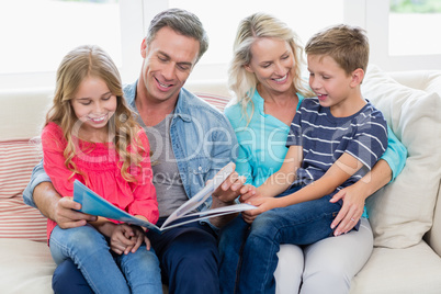 Parents and kids sitting together on sofa looking at photo album