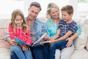 Parents and kids sitting together on sofa looking at photo album