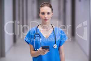 Portrait of female doctor using mobile phone in corridor