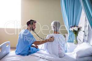 Male doctor examining senior female patient with a stethoscope