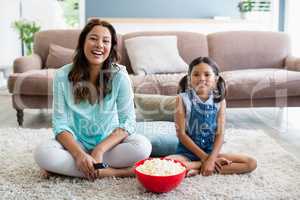 Mother and daughter watching television in living room