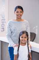 Portrait of smiling mother and daughter standing at counter