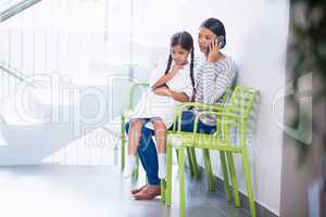 Mother talking on mobile phone while girl sits on her lap