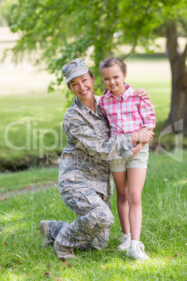 Portrait of happy female soldier with her daughter in park