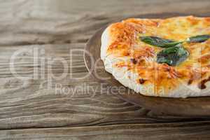 Italian pizza served in a tray on a wooden plank