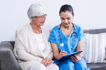 Doctor and senior woman discussing on clipboard