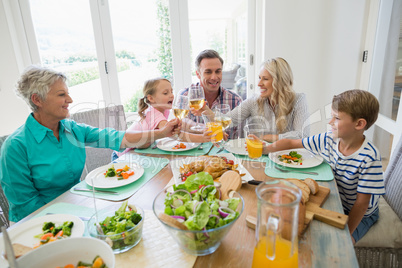 Multi- generation family toasting a glass of wine and juice on dining table