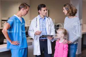 Doctors discussing medical report with mother and daughter