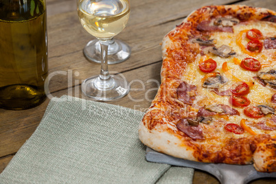 Delicious pizza served on pizza tray with a glasses of wine bottle and wine