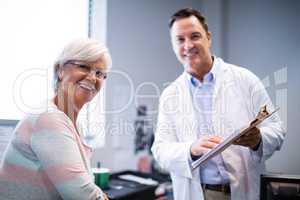 Portrait of doctor and senior patient discussing on clipboard