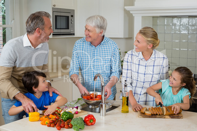 Senior man interacting with his family while preparing food in kitchen