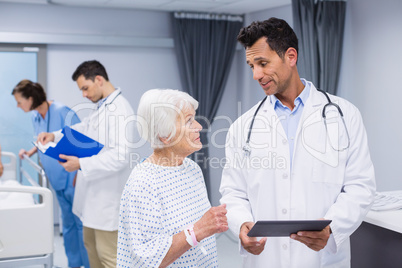 Doctor talking to senior patient while using digital tablet
