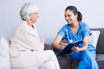 Doctor and senior woman discussing on clipboard