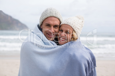 Mature couple wrapped in blanket on the beach