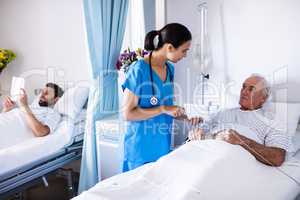 Female doctor discussing with male senior patient over digital tablet