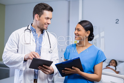 Smiling doctor and nurse using digital tablet and clipboard