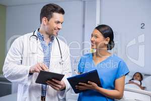 Smiling doctor and nurse using digital tablet and clipboard