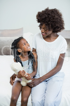 Smiling mother and daughter interacting on bed