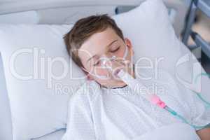 Boy patient wearing oxygen mask lying on hospital bed