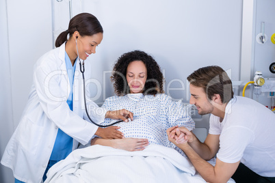 Doctor examining pregnant woman in ward