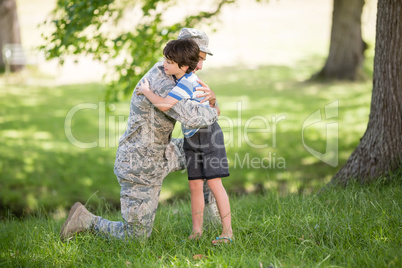 Army soldier embracing boy in park