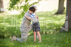 Army soldier embracing boy in park