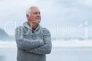 Senior man standing with arms crossed on the beach