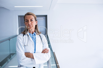 Portrait of female doctor standing with arms crossed in passageway