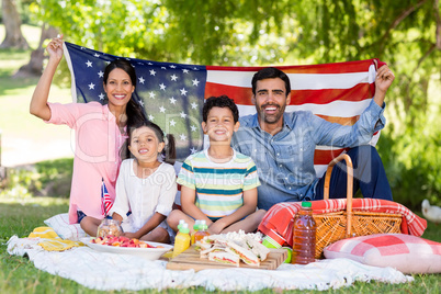 Portrait of happy family holding a american flag in park