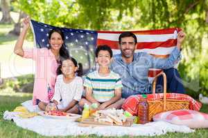Portrait of happy family holding a american flag in park