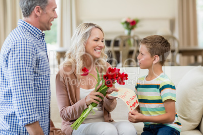Boy giving card and roses to his mother