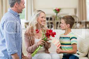 Boy giving card and roses to his mother