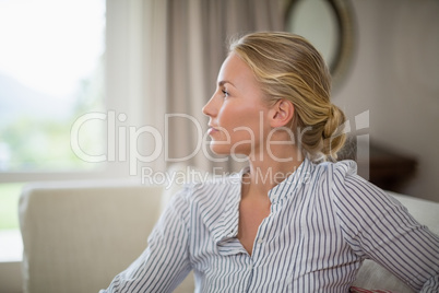 Thoughtful woman sitting on sofa in living room